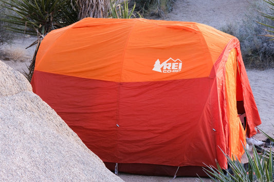 an orange and red tent sitting on top of a rock