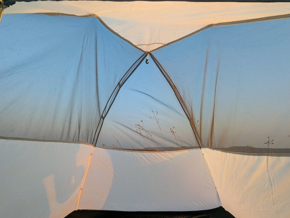 A white tent with a black bag on top of it