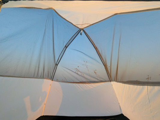 A white tent with a black bag on top of it