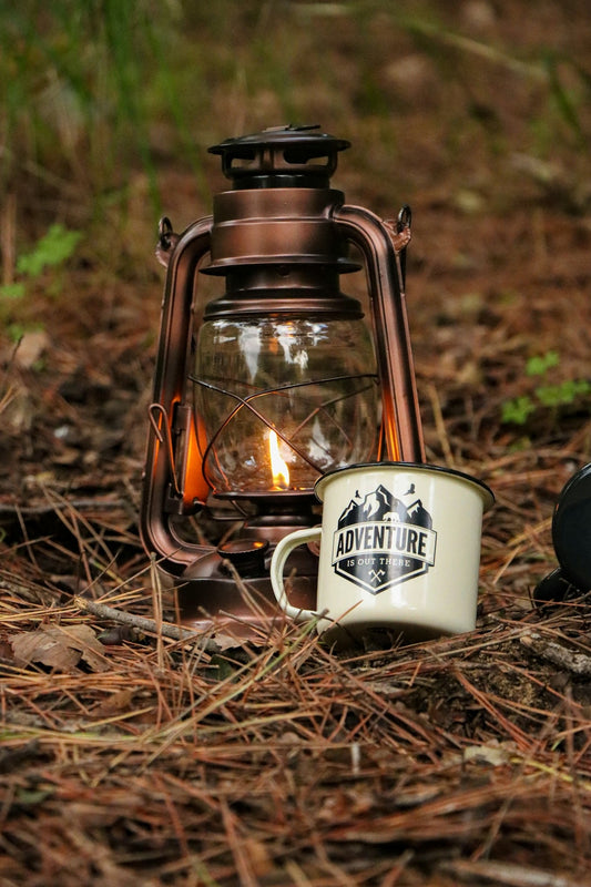 A lantern and a coffee mug sitting on the ground