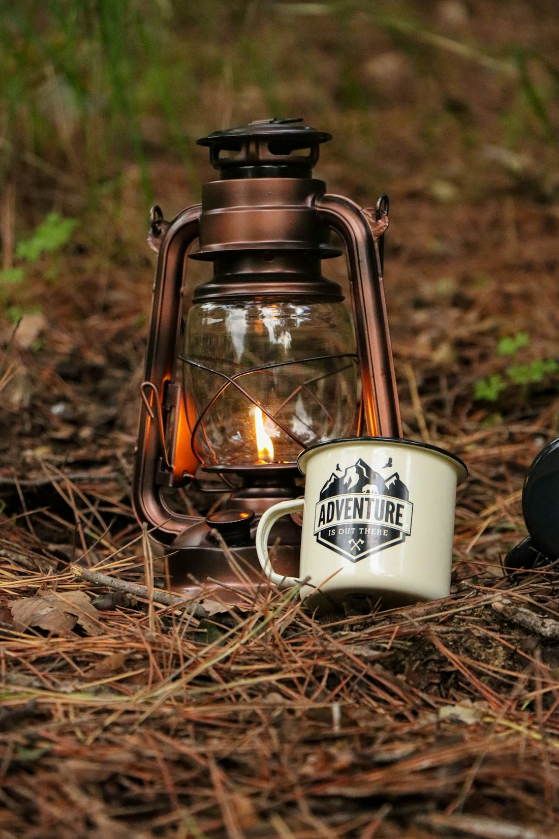 A lantern and a coffee mug sitting on the ground